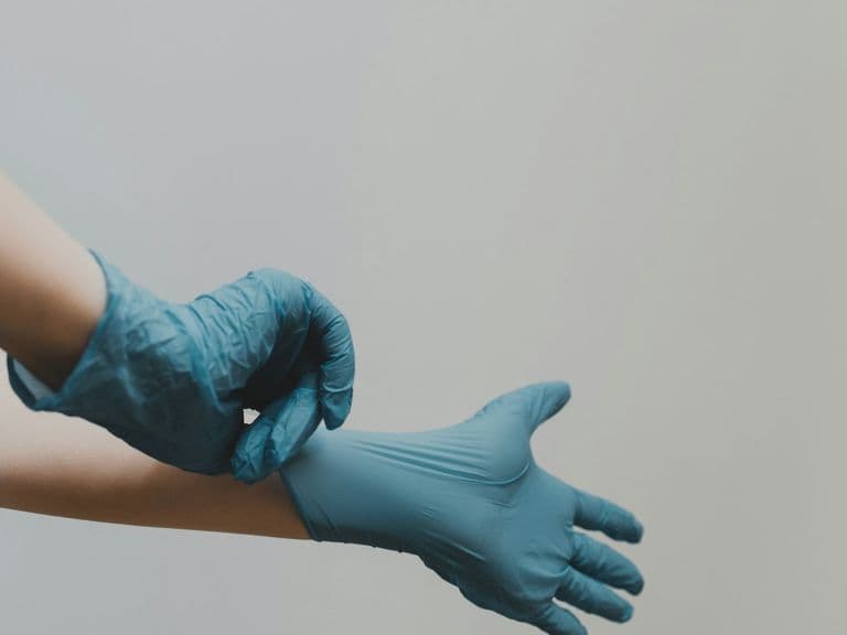 Clinician putting on medical gloves, representing patient safety protocols