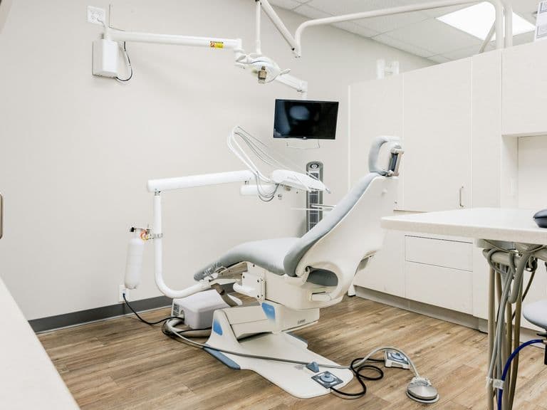 Image of a white dental chair within a white dental room. A day in the life of the dental practice manager at Distinctly Dental.
