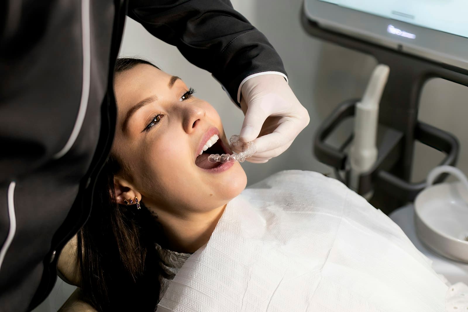 Smiling patient being fitted with a clear dental aligner