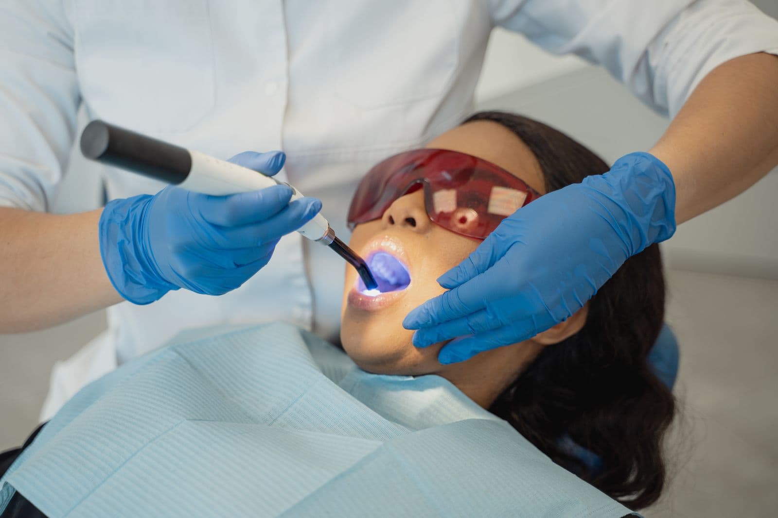 Dentist using a dental curing light to set a white filling
